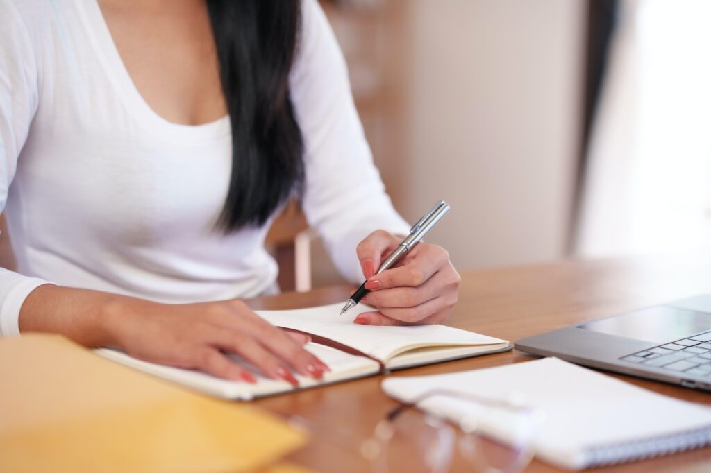 Businesswoman sitting taking notes intensively and doing assigned tasks happily and purposefully.